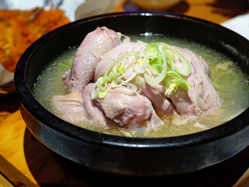 A black bowl of boiled chicken in chicken broth