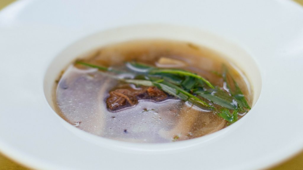 A White Bowl of Grandma's Vegetable Beef Soup With Some Beef Meat and Veggies in It