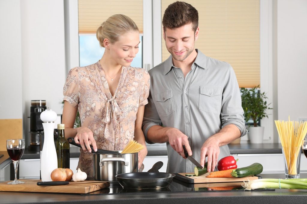 Young man and women prepare meal together in the kitchen and smile