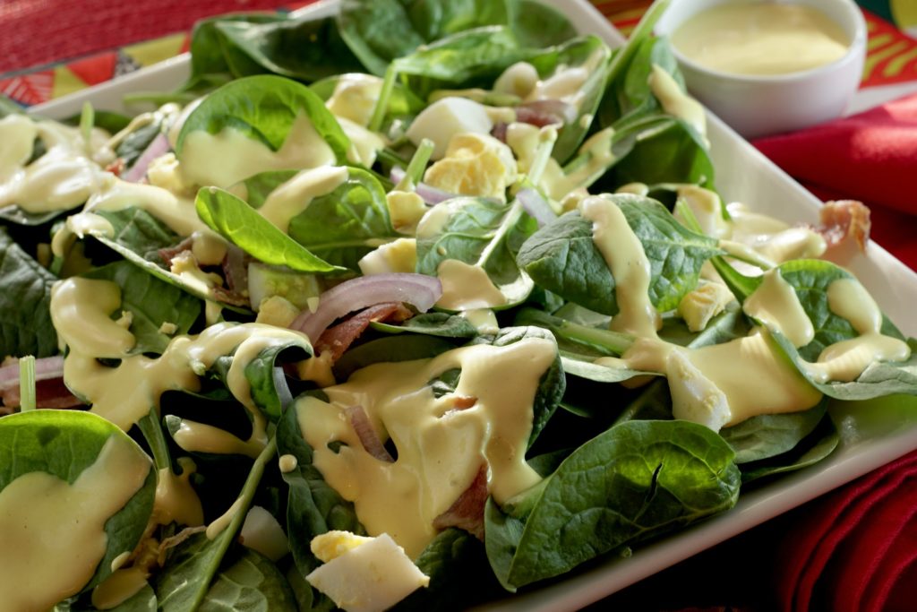 A salad with chopped green leafy vegetables and dressing on them